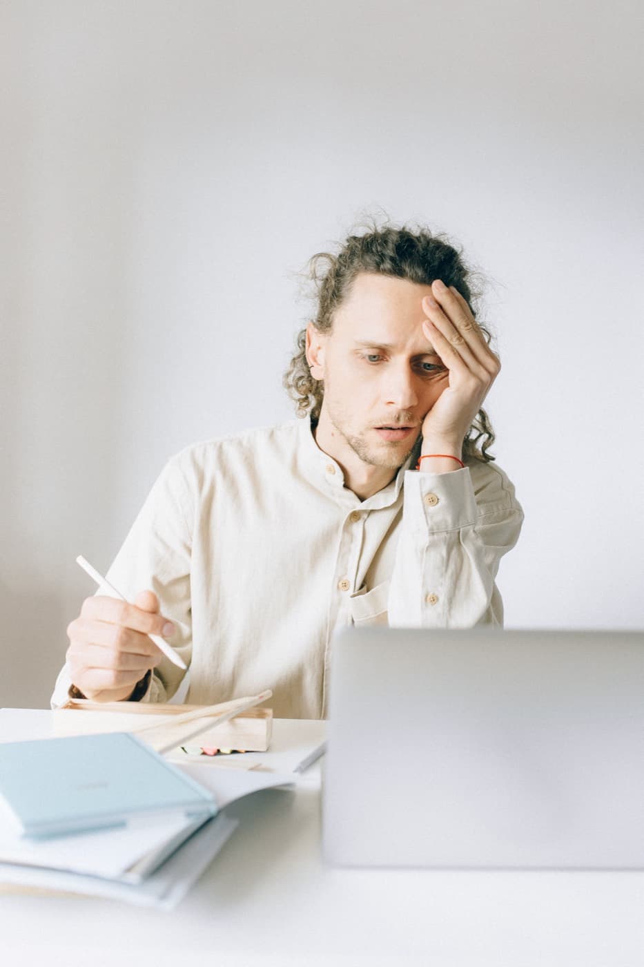 Someone at a desk, head in hand, the work still open in front of them.